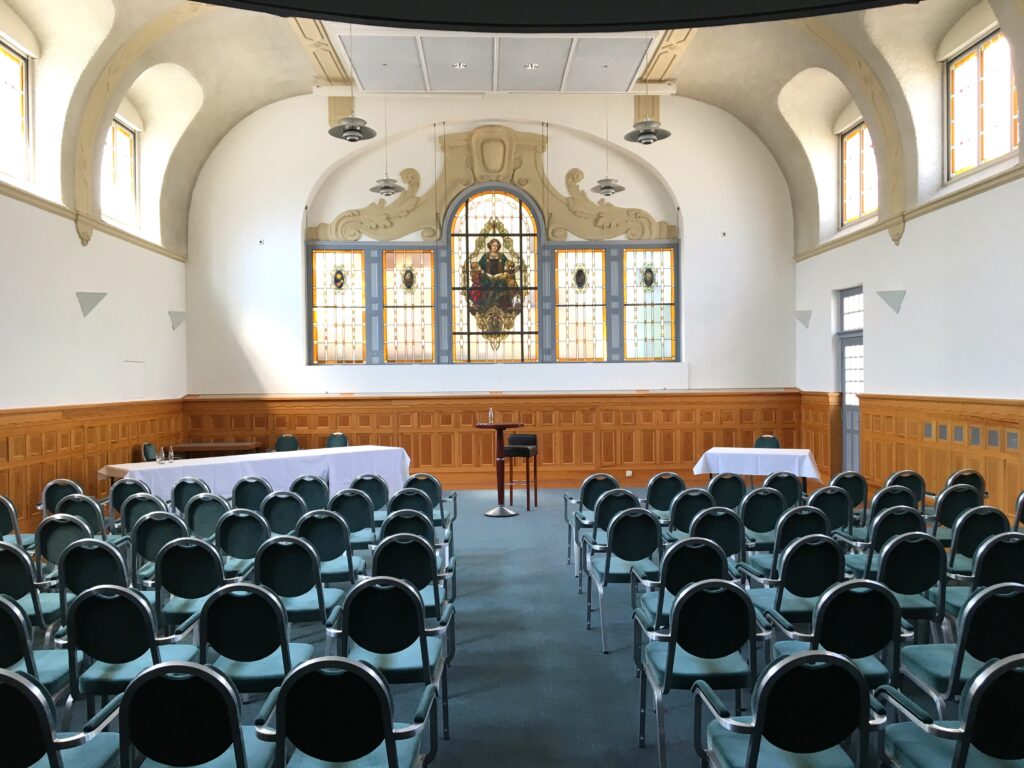 Aula mit einer Reihenbestuhlung mit Blick zur Bühne